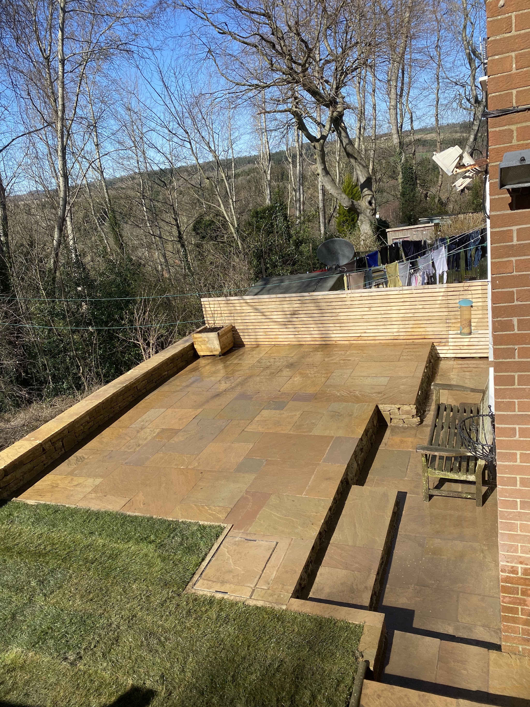 A tiered sandstone patio with sleeper steps down a sloping garden