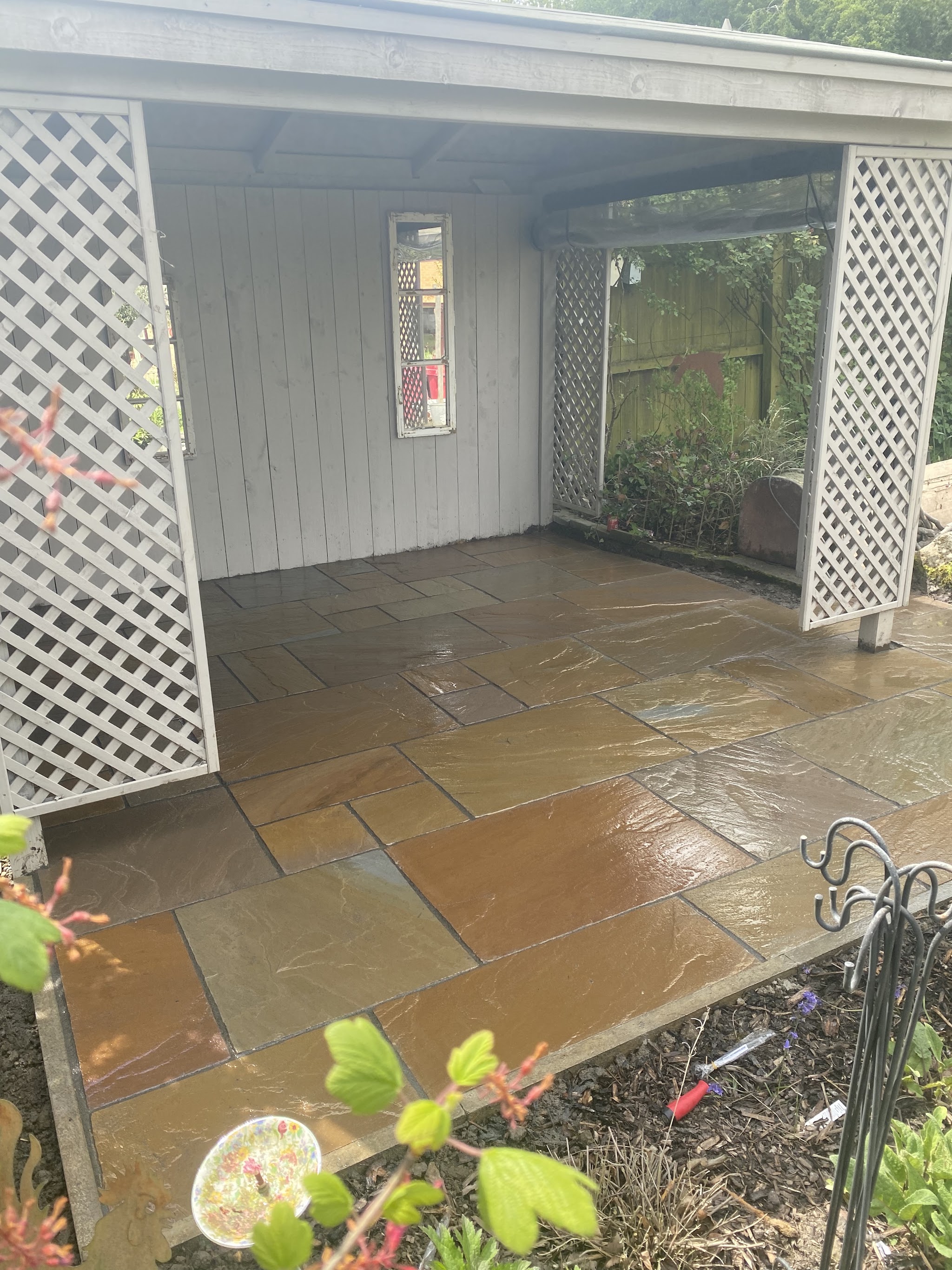 A patio under a white lattice-sided garden room
