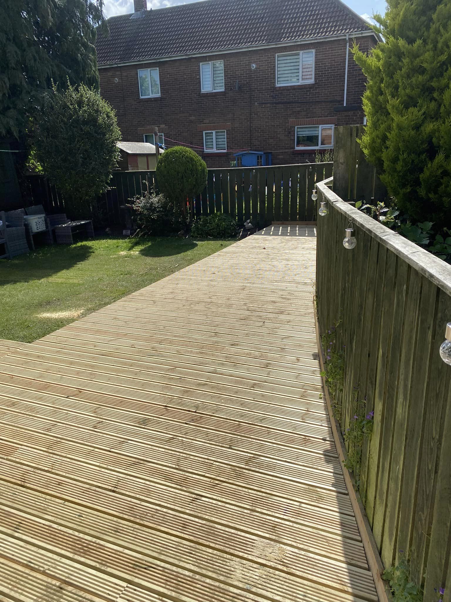 A decked path beside a fence with a lawn