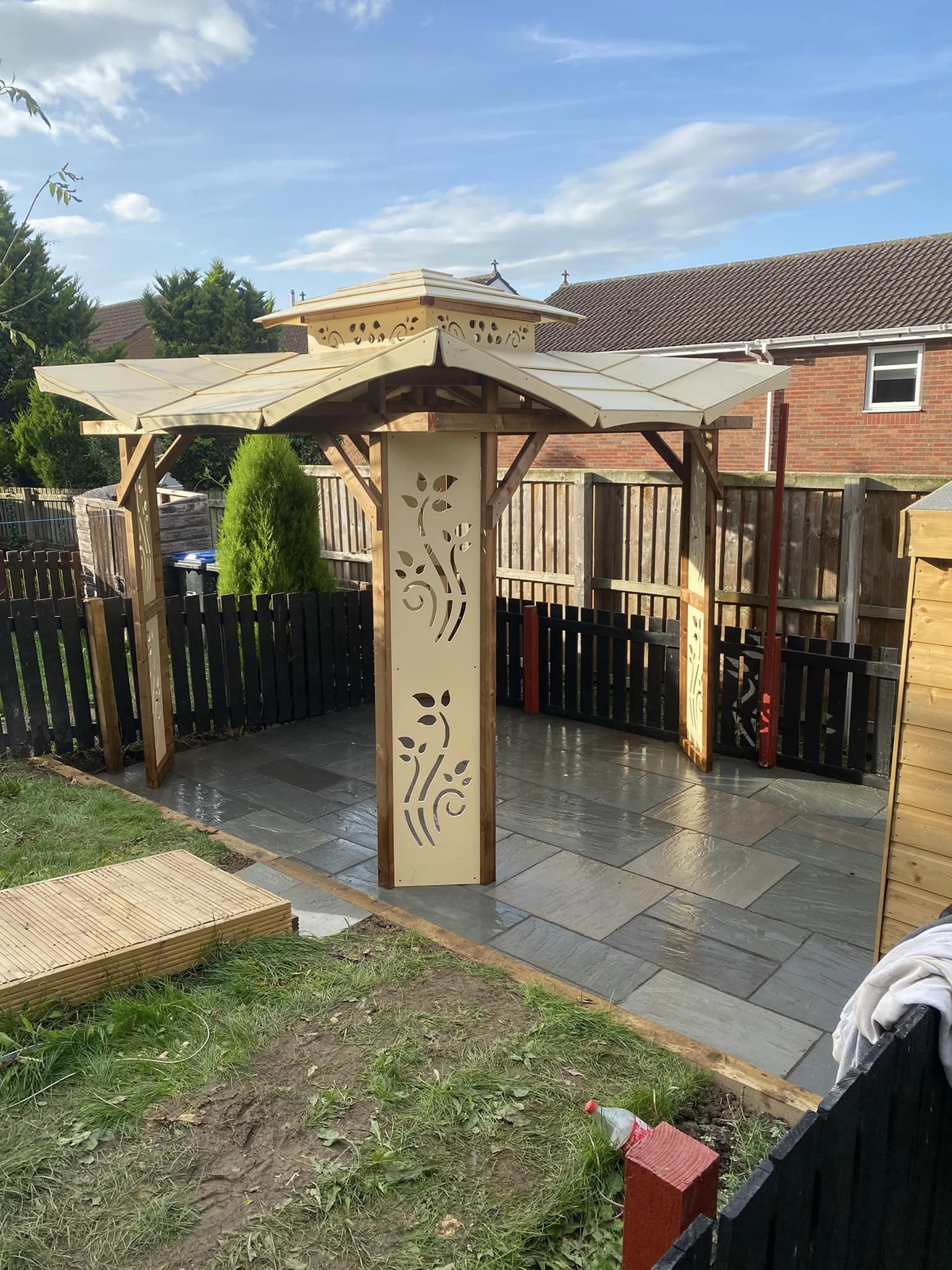 A decorative timber gazebo over a grey slate patio