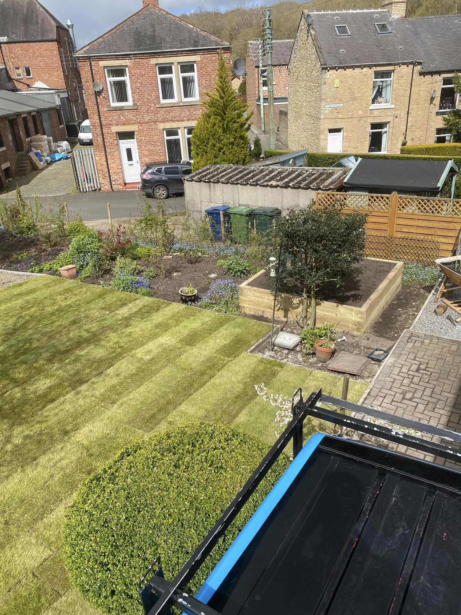 A raised sandstone patio with new turf and timber edging